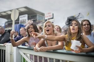Horse racing fans cheering on their horses